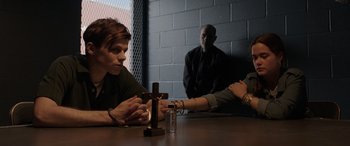 Movie still from “The Conjuring: The Devil Made Me Do It” (2021), directed by Michael Chaves – A group of people sitting at a table with a cross on it; Medium shot, Over the shoulder angle