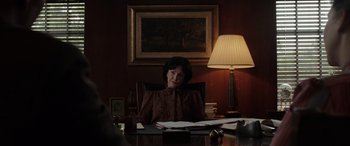 Movie still from “The Conjuring: The Devil Made Me Do It” (2021), directed by Michael Chaves – An older woman sitting at a desk in front of a lamp; Medium shot, Over the shoulder angle
