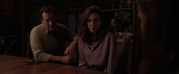 Movie still from “The Conjuring: The Devil Made Me Do It” (2021), directed by Michael Chaves – A woman sitting at a wooden table with a man; Medium shot, High angle