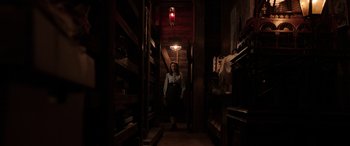 Movie still from “The Conjuring: The Devil Made Me Do It” (2021), directed by Michael Chaves – A woman standing in a dark room with a light hanging from the ceiling; Wide shot, Low angle