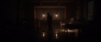 Movie still from “The Conjuring: The Devil Made Me Do It” (2021), directed by Michael Chaves – A man is mopping the floor in the dark; Wide shot, High angle