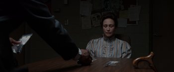 Movie still from “The Conjuring: The Devil Made Me Do It” (2021), directed by Michael Chaves – A woman sitting at a table with a man shaking her hand; Medium shot, Over the shoulder angle
