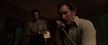 Movie still from “The Conjuring: The Devil Made Me Do It” (2021), directed by Michael Chaves – A man on a phone with a woman in the background; Medium shot, Low angle