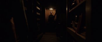 Movie still from “The Conjuring: The Devil Made Me Do It” (2021), directed by Michael Chaves – A person standing in a dark room with a light on; Wide shot, Low angle