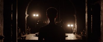 Movie still from “The Conjuring: The Devil Made Me Do It” (2021), directed by Michael Chaves – A person standing in front of lights in a dark room; Medium shot, Low angle