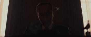 Movie still from “The Courier” (2020), directed by Dominic Cooke – A man in a suit and tie smoking a cigarette; Close Up shot, Low angle