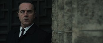 Movie still from “The Courier” (2020), directed by Dominic Cooke – A man standing next to a stone wall; Close Up shot, Low angle