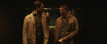 Movie still from “The Courier” (2020), directed by Dominic Cooke – Two men standing next to each other in front of a staircase; Medium shot, Low angle