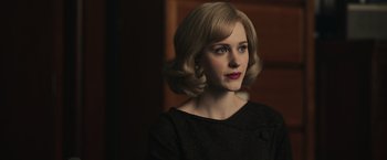 Movie still from “The Courier” (2020), directed by Dominic Cooke – A woman with blonde hair and red lipstick looking to her left; Close Up shot, Over the shoulder angle