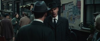 Movie still from “The Courier” (2020), directed by Dominic Cooke – A man in a suit and a hat looking at himself in the mirror; Medium shot, Over the shoulder angle