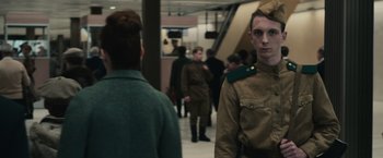 Movie still from “The Courier” (2020), directed by Dominic Cooke – A group of men in uniform walking down a hall way; Medium shot, Over the shoulder angle