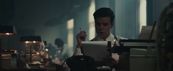 Movie still from “The Courier” (2020), directed by Dominic Cooke – A man is writing on a piece of paper while smoking a cigarette; Medium shot, Low angle