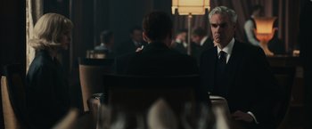 Movie still from “The Courier” (2020), directed by Dominic Cooke – Two men in suits are sitting at a dinner table; Medium shot, Over the shoulder angle