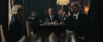 Movie still from “The Courier” (2020), directed by Dominic Cooke – A group of people sitting at a table with wine glasses; Medium shot, Over the shoulder angle