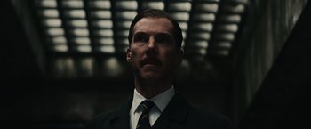 Movie still from “The Courier” (2020), directed by Dominic Cooke – A man wearing a suit and tie in front of lights; Close Up shot, Low angle