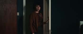 Movie still from “The Courier” (2020), directed by Dominic Cooke – A woman standing in front of a white door; Medium shot, Over the shoulder angle