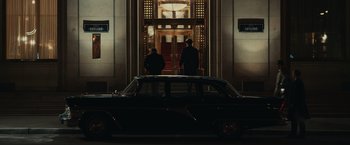 Movie still from “The Courier” (2020), directed by Dominic Cooke – Two men standing in front of an entrance to a building; Extreme Wide shot, Low angle