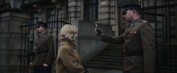 Movie still from “The Courier” (2020), directed by Dominic Cooke – A woman in a brown coat is looking at a man in a green suit; Medium shot, Over the shoulder angle