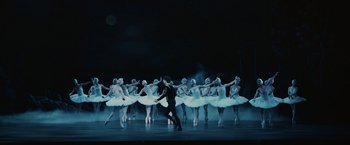 Movie still from “The Courier” (2020), directed by Dominic Cooke – A group of ballerinas in white tutus on a stage; Extreme Wide shot, Low angle