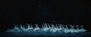 Movie still from “The Courier” (2020), directed by Dominic Cooke – A group of ballerinas in white tutus on a stage; Extreme Wide shot, High angle