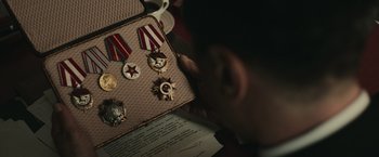 Movie still from “The Courier” (2020), directed by Dominic Cooke – A person looking at medals on a box; Close Up shot, High angle