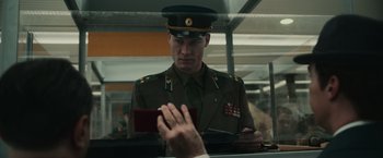 Movie still from “The Courier” (2020), directed by Dominic Cooke – A man in a military uniform looking at his cell phone; Close Up shot, Low angle