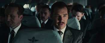 Movie still from “The Courier” (2020), directed by Dominic Cooke – A man in a suit and tie on a bus; Close Up shot, Low angle