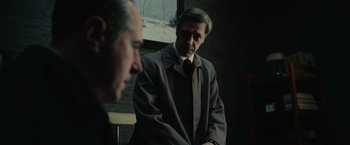 Movie still from “The Courier” (2020), directed by Dominic Cooke – A man in a suit and tie standing next to another man in a suit and tie; Medium shot, Over the shoulder angle