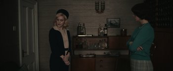 Movie still from “The Courier” (2020), directed by Dominic Cooke – A woman standing in front of a shelf with bottles of alcohol; Medium shot, Low angle
