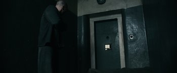 Movie still from “The Courier” (2020), directed by Dominic Cooke – A man standing in front of a green door; Wide shot, High angle
