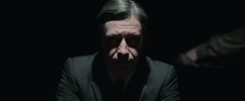 Movie still from “The Courier” (2020), directed by Dominic Cooke – A man in a suit and tie in the dark; Close Up shot, Low angle