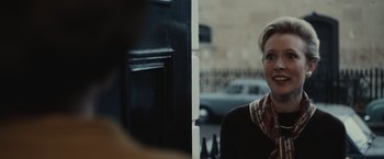 Movie still from “The Courier” (2020), directed by Dominic Cooke – A woman standing in front of a building with bottles; Close Up shot, Over the shoulder angle