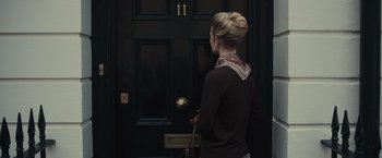 Movie still from “The Courier” (2020), directed by Dominic Cooke – A woman standing in front of a black door; Medium shot, High angle