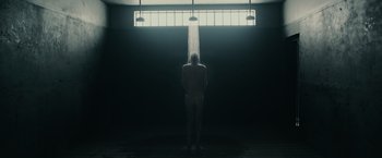 Movie still from “The Courier” (2020), directed by Dominic Cooke – A man standing in a dark room under a window; Wide shot, Low angle