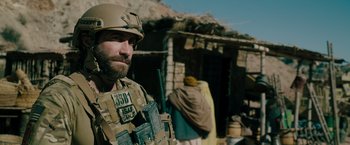 Movie still from “The Covenant” (2023), directed by Guy Ritchie – A man in a military uniform standing in front of a building; Medium shot, Over the shoulder angle
