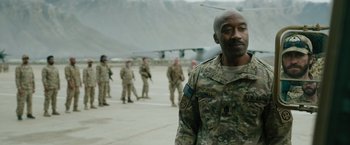 Movie still from “The Covenant” (2023), directed by Guy Ritchie – A man in a military uniform standing in front of an airplane; Medium shot, Over the shoulder angle