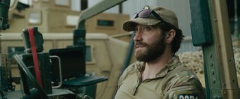 Movie still from “The Covenant” (2023), directed by Guy Ritchie – A man with a beard wearing a hat and glasses; Close Up shot, Over the shoulder angle