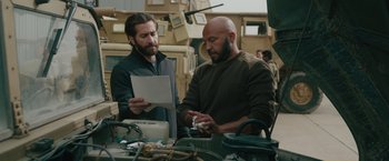 Movie still from “The Covenant” (2023), directed by Guy Ritchie – Two men are looking at a piece of paper in a workshop; Medium shot, Over the shoulder angle