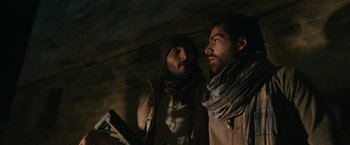 Movie still from “The Covenant” (2023), directed by Guy Ritchie – Two bearded men are standing in a dimly - lit room; Close Up shot, Over the shoulder angle