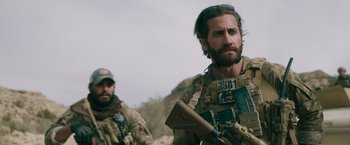 Movie still from “The Covenant” (2023), directed by Guy Ritchie – Two men in military uniforms one is holding a rifle; Medium shot, Over the shoulder angle