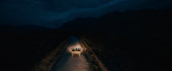 Movie still from “The Covenant” (2023), directed by Guy Ritchie – A truck is driving down a road at night; Extreme Wide shot, High angle