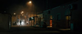 Movie still from “The Covenant” (2023), directed by Guy Ritchie – Two people sitting on the side of the road at night; Extreme Wide shot, Low angle