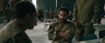 Movie still from “The Covenant” (2023), directed by Guy Ritchie – A man in a military uniform sitting next to a woman; Medium shot, Over the shoulder angle