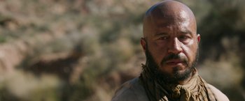 Movie still from “The Covenant” (2023), directed by Guy Ritchie – A bald man with a beard and a mustache; Close Up shot, Low angle