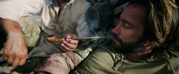 Movie still from “The Covenant” (2023), directed by Guy Ritchie – A man smoking a pipe while sitting on a couch; Close Up shot, High angle