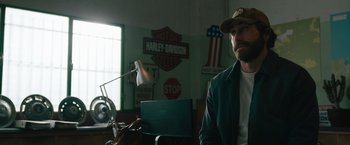 Movie still from “The Covenant” (2023), directed by Guy Ritchie – A man sitting in front of a laptop computer; Medium shot, Over the shoulder angle