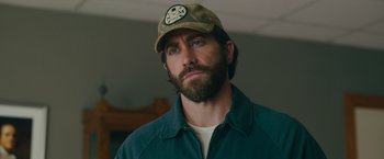 Movie still from “The Covenant” (2023), directed by Guy Ritchie – A person wearing a hat; Close Up shot, Over the shoulder angle