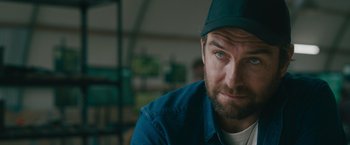 Movie still from “The Covenant” (2023), directed by Guy Ritchie – A person wearing a hat; Close Up shot, Over the shoulder angle