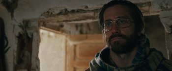 Movie still from “The Covenant” (2023), directed by Guy Ritchie – A man with a beard wearing glasses and a scarf; Close Up shot, Low angle