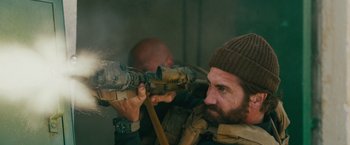 Movie still from “The Covenant” (2023), directed by Guy Ritchie – A man with a beard is looking through a scope; Close Up shot, Over the shoulder angle